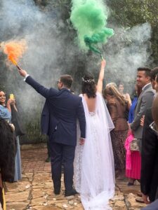 Celebración de boda con humo verde, novio en traje azul de espalda.