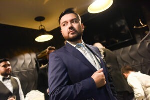 Retrato de novio de perfil mirando a lo lejos, luciendo un traje azul impecable.