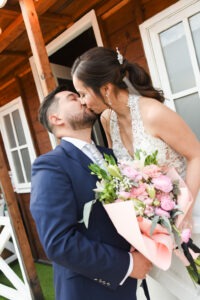 Novios besándose al aire libre, él con traje azul elegante.