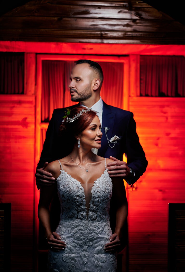 Pareja en ambiente con luz roja, novio viste traje azul oscuro.