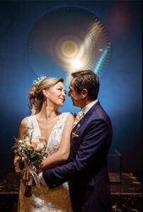 Pareja abrazada en fondo azul, novio con traje azul a la medida.