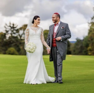 Novio caminando de la mano vistiendo un chaqué gris tradicional.