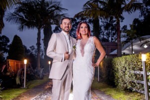 Novios posando de noche, él luce un traje claro de alta costura.