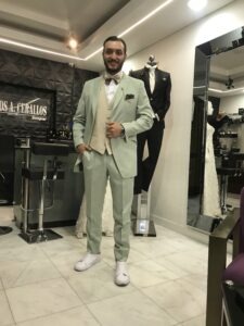 Novio posando en interior con un traje verde menta exclusivo.