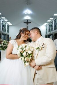 Novios en iglesia, él viste traje crema exclusivo de sastrería.