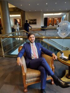 Novio sentado en silla de cuero con un traje azul de diseño.