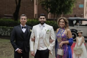Novio y padrinos caminando con trajes claros.