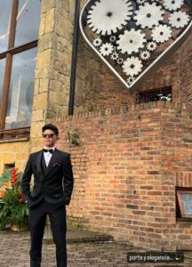 Novio posando en exterior con traje negro clásico.