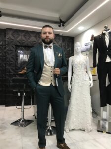 Caballero modelando un traje verde oscuro de alta costura.