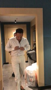 Novio ajustando su camisa blanca frente al espejo.