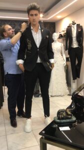 Novio posando en la boutique con un traje oscuro de solapa texturizada.
