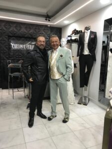 Dos caballeros luciendo trajes exclusivos en tonos gris claro y negro.