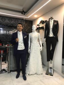 Novio elegante con traje oscuro y chaleco claro junto a maniquí de novia.