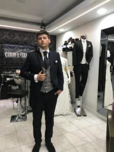 Cliente posando seguro con su traje negro formal en la sastrería.