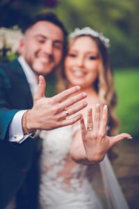 Primer plano de las manos de los novios luciendo sus anillos de matrimonio.