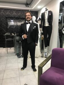 Caballero posando de pie con un smoking negro clásico de alta costura.