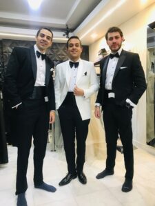 Dos caballeros luciendo contrastantes smokings de etiqueta en blanco y negro.