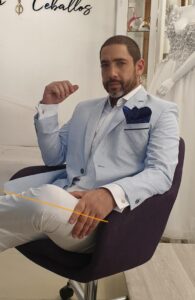 Caballero sentado proyectando seguridad con un traje celeste a la medida.