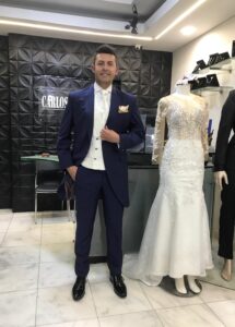 Novio vistiendo un elegante traje azul marino con chaleco claro en la boutique.