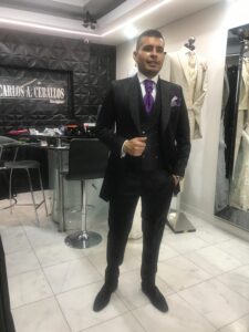 Caballero luciendo un impecable smoking negro con chaleco de alta costura en el atelier.