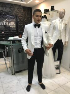 Novio posando con chaqueta blanca y pantalón negro.