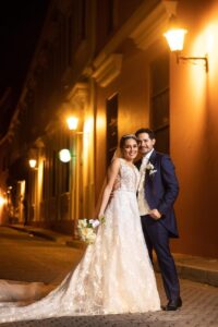 Pareja caminando de noche, él luce traje azul rey.