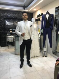 Caballero posando junto a maniquí con traje blanco.
